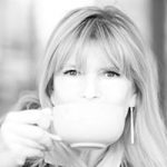 Black-and-white portrait of a person with long light hair holding a large cup close to their face, looking directly at the camera against a softly blurred background.